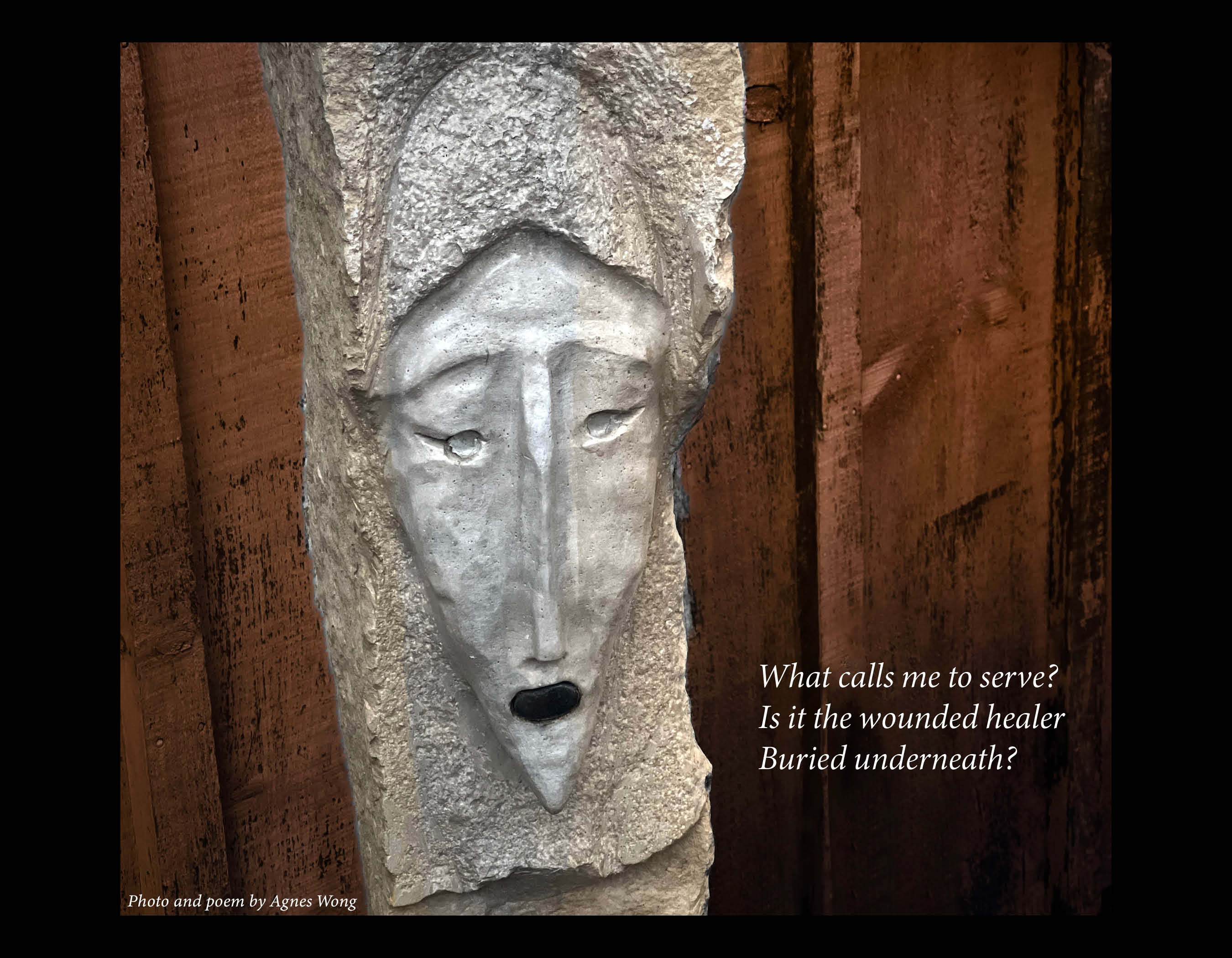 A carved stone face against weathered brown wooden panels.